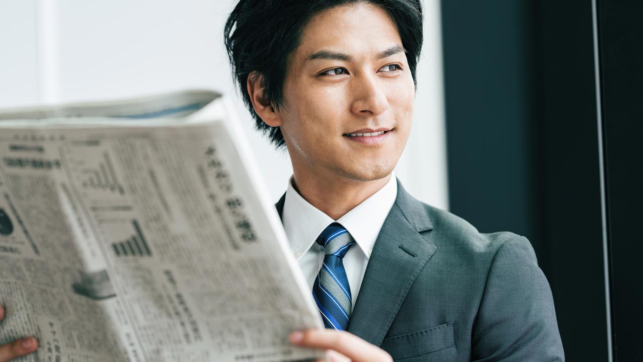 新聞を読むオフィスワーカーの画像